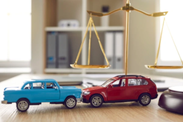 Zwei Modellautos vor einer Justitia-Waage, &copy; Studio Romantic/Shutterstock.com